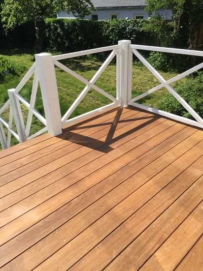 Solidt tømrerarbejde - nylagt terrasse med brune træplanker og hvidt gelænder
